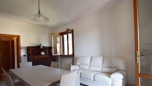 A dining area with a table and chairs, a white sofa, and a wooden cabinet with a mirror. - Holiday Apartment Ciliegio, Marina di Campo convenient for the beach and center. (Marina di Campo)