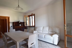 Ein Essbereich mit Tisch und Stühlen, einem weißen Sofa und einer Holzkommode mit Spiegel.