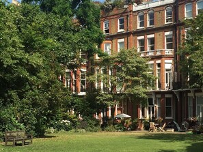 A row of red brick townhouses with a well-maintained garden in the foreground.