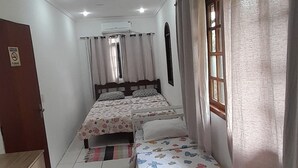 A bedroom with two beds, a wooden wardrobe, and a window with curtains. - Casa de Maria (Angra dos Reis)