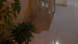 A cozy patio area with a table and chairs, surrounded by potted plants and a window with decorative glass. - Casa de Maria (Angra dos Reis)