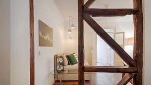Une pièce avec un plancher en bois, un canapé avec des coussins, une table en verre et un tableau accroché au mur.