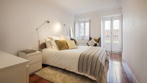 Une chambre à coucher avec un lit, des tables de chevet, un bureau et une fenêtre.