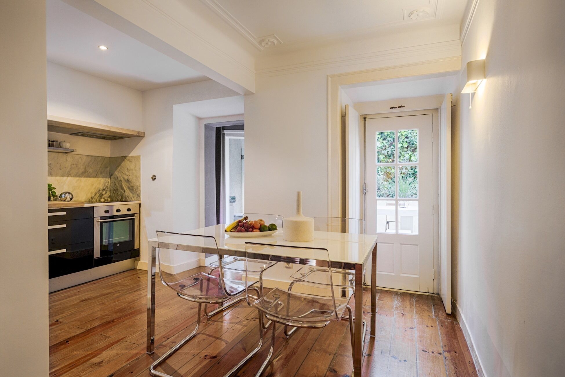 Une cuisine moderne dotée d’un four encastré et d’un coin repas avec une table et des chaises en verre.