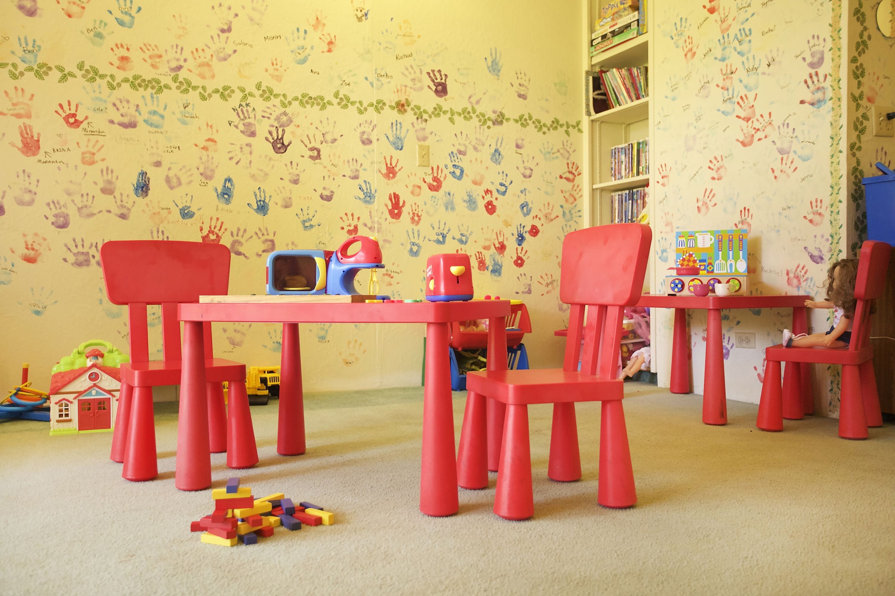 Una sala giochi per bambini con mobili rossi, una libreria e un pavimento rivestito di moquette.