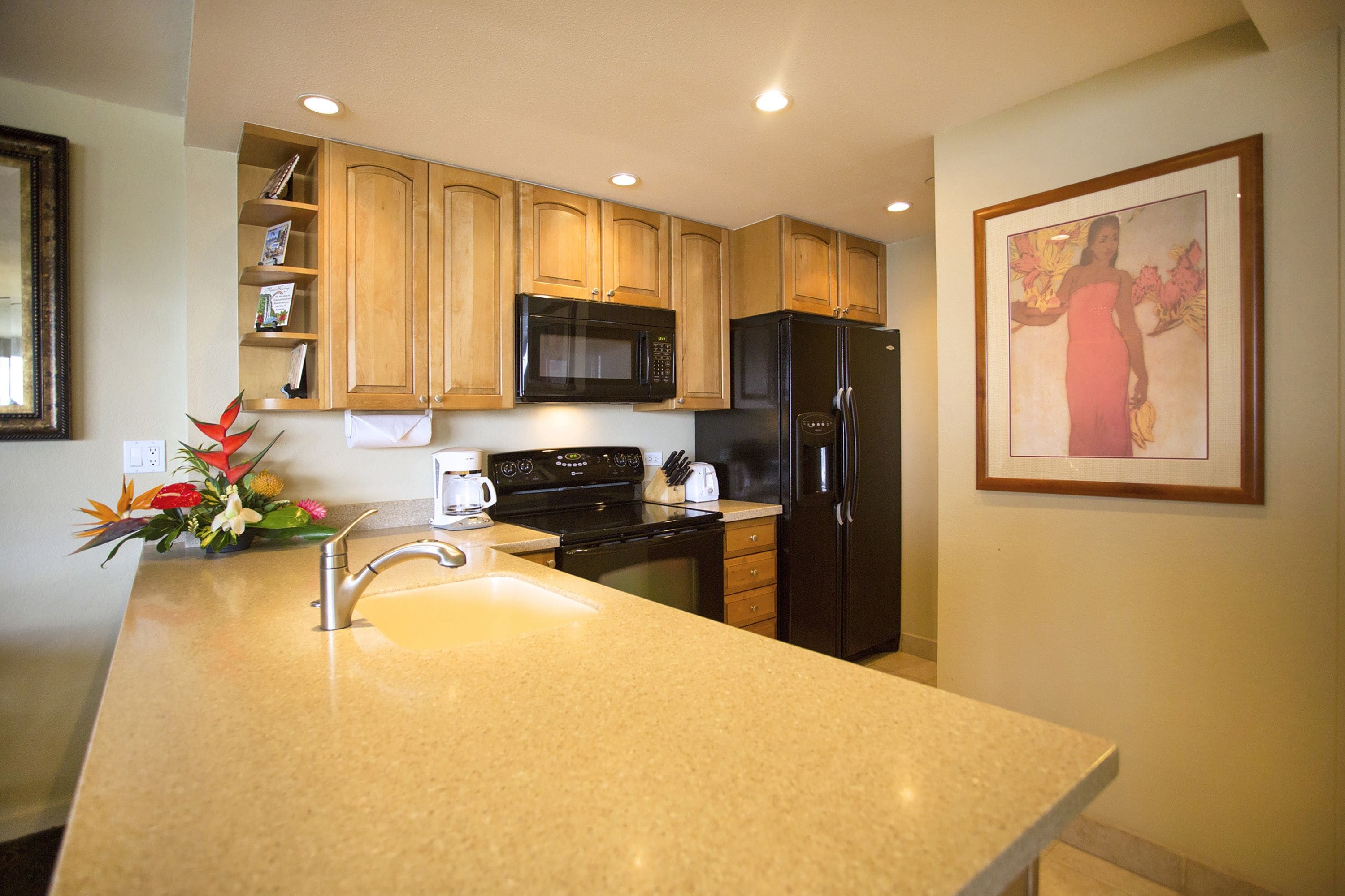 A kitchen with wooden cabinets, a black refrigerator, a microwave, and a sink.
