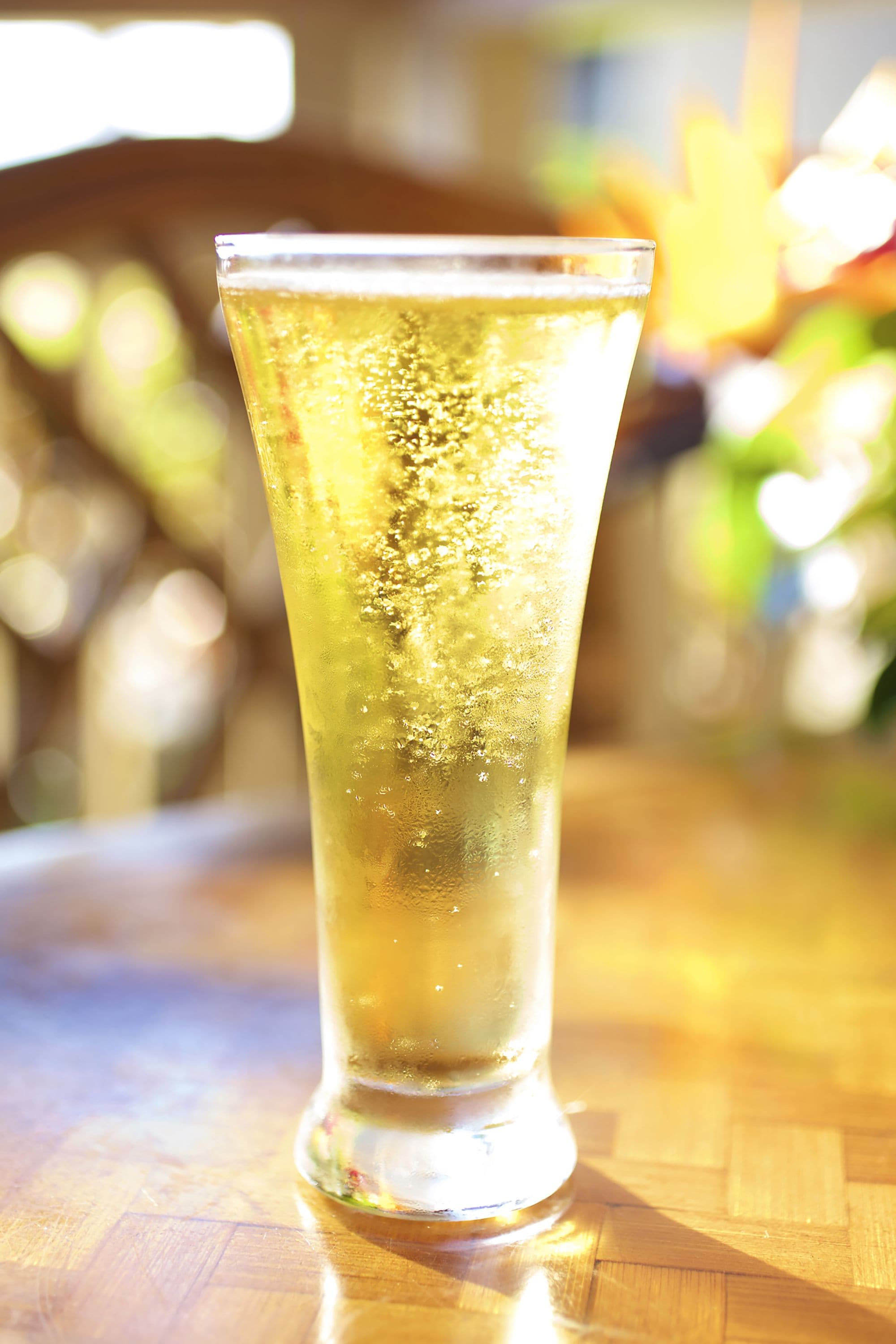 A tall glass with a beverage on a wooden surface.