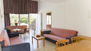 A living room with a sofa, chairs, a table, and a window with curtains. - Eliofos Elegant Maisonettes (Polis)