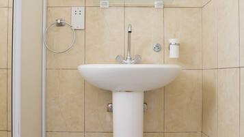 A bathroom with a white sink, a mirror, and beige tiles.