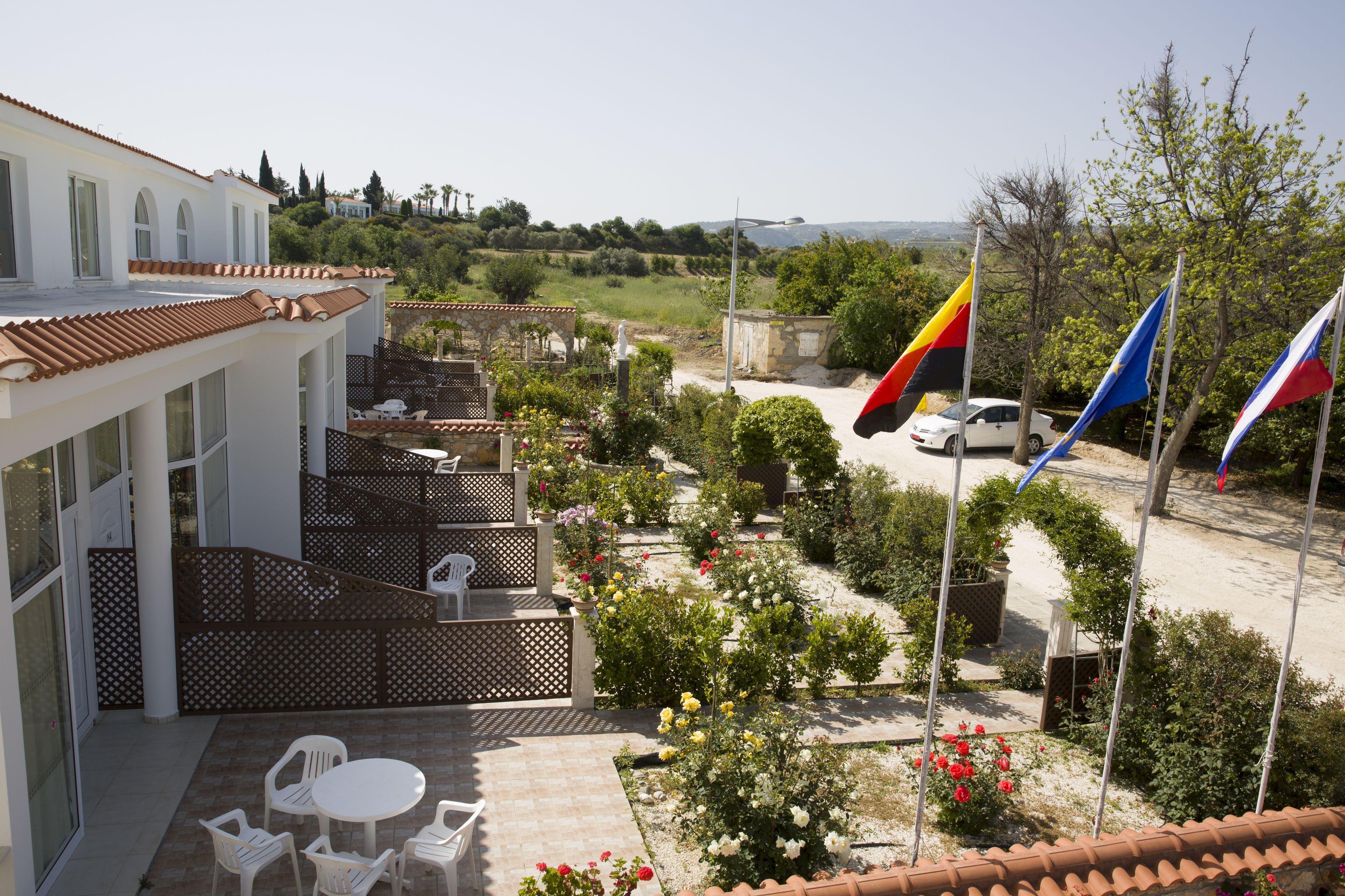 Un patio de hotel con mobiliario exterior, vistas al campo y banderas.