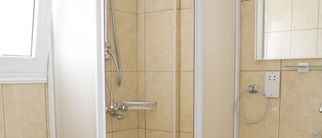 A bathroom with a toilet, a shower with a glass door, and a sink.