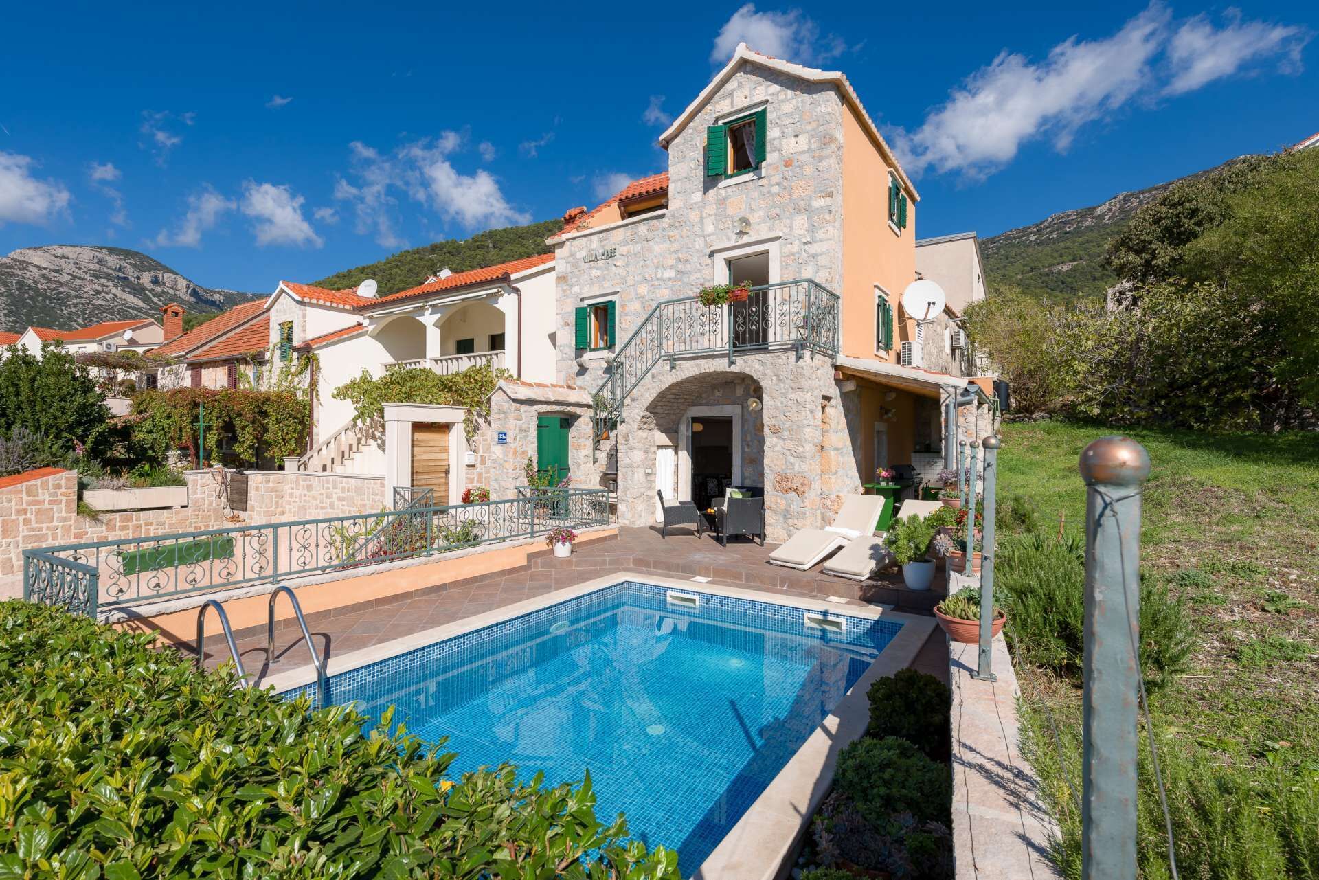 Uma vila de pedra com piscina, varanda e vista para as colinas ao redor.