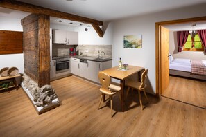 Une cuisine compacte dotée d’appareils modernes, un coin repas avec des meubles en bois et une chambre avec vue sur l’extérieur.
