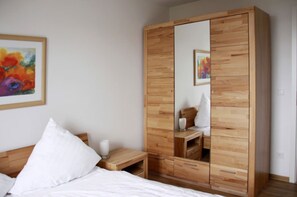 Ein Schlafzimmer mit einem Holzschrank, einem Nachttisch, einem Spiegel und einem Bild an der Wand.