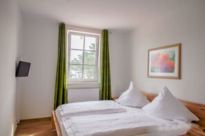 A neatly made bed with white linens, a window with green curtains, and a framed picture on the wall. - Haus Meeresblick Fewo Am Wasser A 3.09 Ref. 134062 - Holiday apartment Am Wasser A (Baabe)