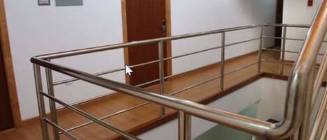 A staircase with metal railings and wooden steps, leading to a landing area with a door and a sign on the wall.