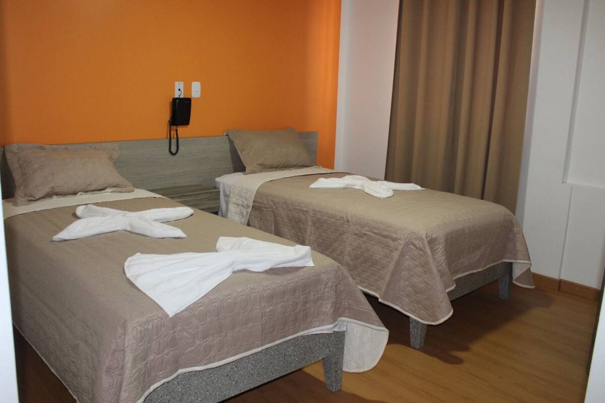 Una habitación de hotel con dos camas, un teléfono y una cortina.