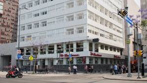 Een meerhoog gebouw met een plat gevelvlak, grote ramen en een commercieel gebied op de begane grond met winkels.