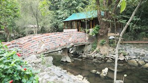 Un puente de ladrillo sobre un arroyo con una estructura de madera a la derecha.