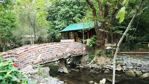 Un puente de ladrillo sobre un arroyo con una estructura tipo pabellón a la derecha.