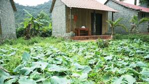 Un edificio rústico con tejado de tejas, rodeado de abundante vegetación y un jardín.