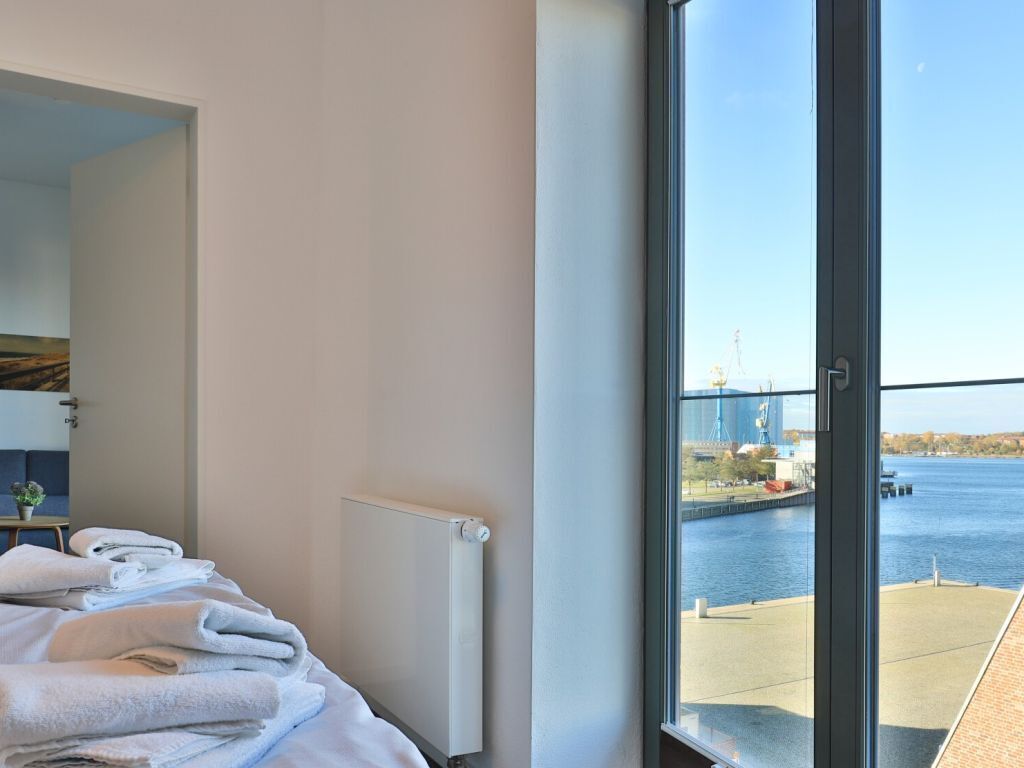 Een hotelkamer met een bed, een radiator en uitzicht op een brug over het water.