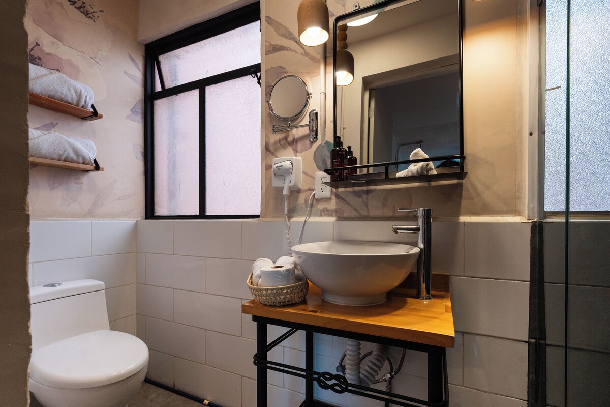 A bathroom with a white toilet, a large sink, a mirror, and a window.
