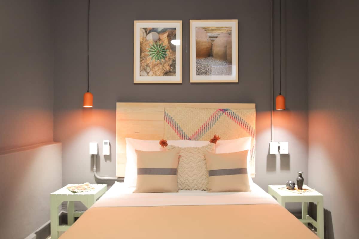 A neatly arranged bedroom with a large bed, two bedside tables, and two wall-mounted lamps.