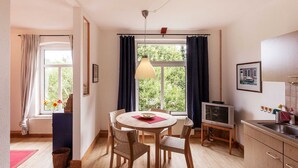 A cozy kitchen with a dining table, chairs, a TV, and a window with curtains. - Old village pitcher FW 3 - FW 3, north-east (Kronsgaard)