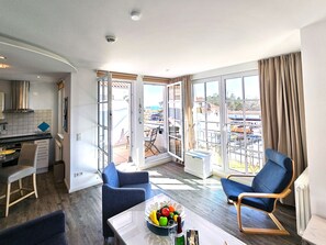Una sala de estar moderna con comedor, ventanas grandes y vistas a la ciudad.