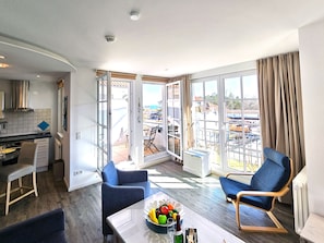 Una sala de estar moderna con comedor, ventanas grandes y vistas a la ciudad.