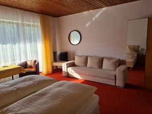A hotel room with a bed, a sofa, a TV, and a mirror.