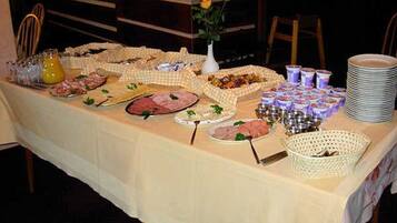 Ein reichhaltiges Buffet mit verschiedenen Speisen, darunter Fleisch und Gebäck, auf einer Tischdecke.