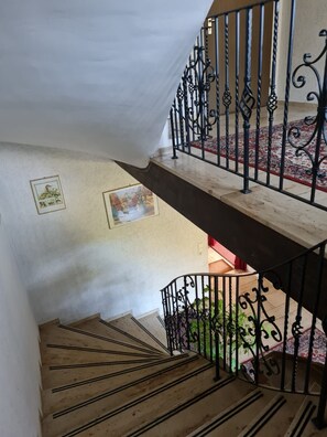 A staircase with a wooden handrail and black wrought iron balustrades. - Double room no. 22 - Waldpension Rabeneck (Waischenfeld)
