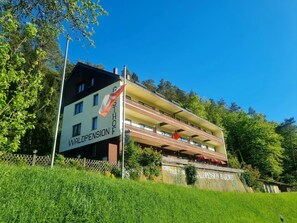 Monikerroksinen rakennus, jossa on parvekkeita, lippu ja kyltti, jossa lukee: »WALDPENSION RABENFOG».
