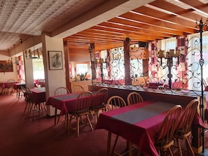 A restaurant with wooden beams, red tablecloths, and metal railings.