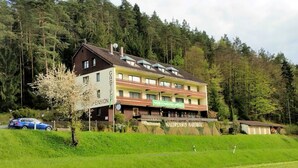 Un immeuble à plusieurs étages, sur lequel on peut lire l’enseigne « GASTHOF WALDPENSION RABENECK », et qui abrite un restaurant appelé « café et restaurant ».