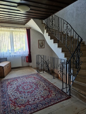 A staircase with ornate black railings, a wooden floor, and a patterned rug. - Double room no. 22 - Waldpension Rabeneck (Waischenfeld)