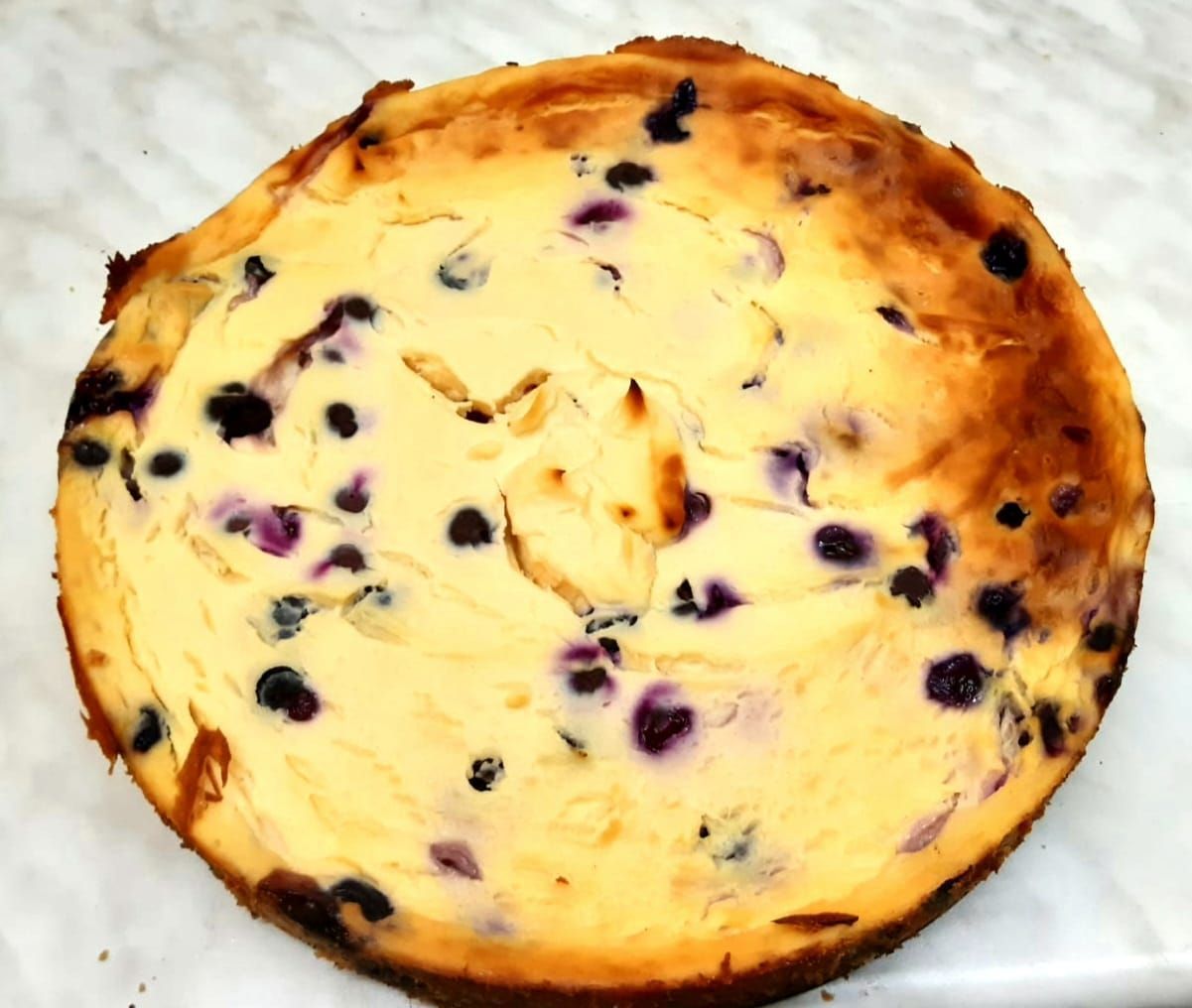 Ein runder, gebackener Kuchen mit goldbrauner Kruste und sichtbaren Fruchtstücken.