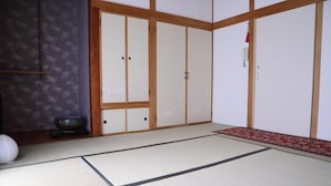Une pièce de style japonais traditionnel, avec un sol recouvert de tatamis, des portes coulissantes et un tapis rouge à motifs.