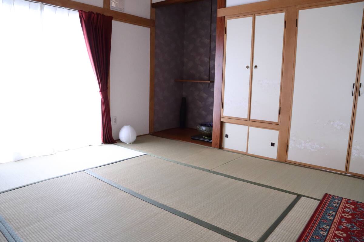 Una habitación tradicional japonesa con suelo de tatami, un shoji y puertas correderas.