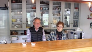 Une cuisine dotée de plans de travail en bois, d’un four à micro-ondes et d’armoires en verre contenant de la vaisselle.