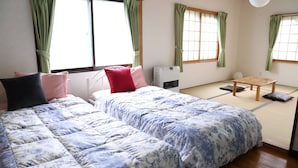 Une pièce de style japonais traditionnel, avec un sol recouvert de tatamis, deux tapis de tatami, une petite table en bois et un futon avec une literie à motifs floraux.