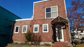 A red brick building with a small porch, a single window, and a door.