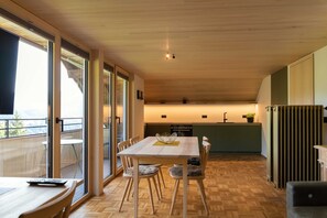 Eine moderne Küche mit Essbereich, Holzboden und großen Fenstern.