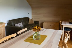 Une table à manger ornée d’un vase de fleurs, des chaises en bois, une table en bois et un plafond en bois.