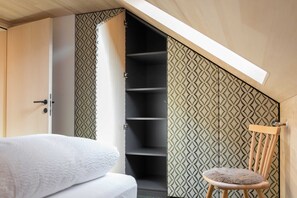 Een slaapkamer met een bed, een stoel, een kledingkast en een dakraam.