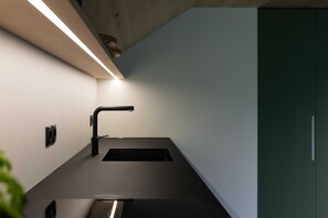 A modern kitchen with a black countertop, a sink, and a light fixture above. - Vacation apartment Ifen - Haus Sonnenblick (Sibratsgfäll)