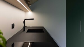 A modern kitchen with a black countertop, a sink, and a light fixture above.