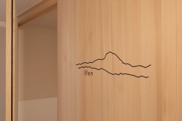 Une porte en bois ornée d’un simple dessin représentant une montagne et portant le mot « Ifen ».